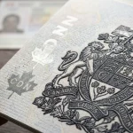 Close-up of textured printing and a coat of arms on a passport page held in a hand